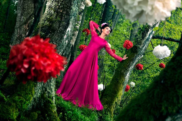 Mujer en vestido largo de color rosa en la madera —  Fotos de Stock