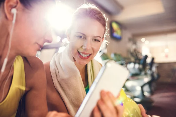 Twee passen vrouwen in sportschool met smartphone — Stockfoto