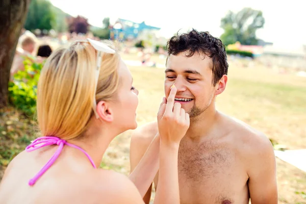 Frau setzt Mann Sonnencreme auf Nase — Stockfoto