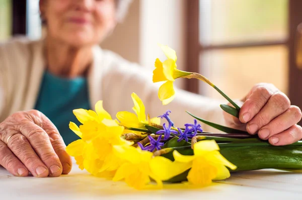 Mulher sênior segurando buquê de narcisos — Fotografia de Stock