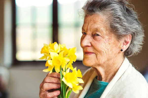 Mulher sênior segurando buquê de narcisos — Fotografia de Stock