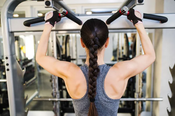 Mulher no ginásio flexionando os músculos das costas — Fotografia de Stock