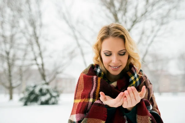 Женщина в одеяле ловит снежинки — стоковое фото