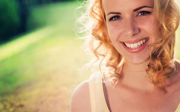 Blond woman, curly hair in green nature. Sunny summer — Stock fotografie