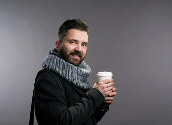 Man in winter clothes holding coffee cup. Studio shot — Stock Photo, Image