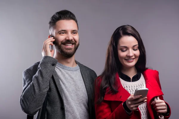 Young woman and man in winter clothes with smartphone — Stockfoto