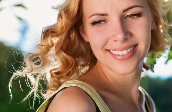 Blond woman, flipping curly hair. Sunny summer nature. — Stok fotoğraf