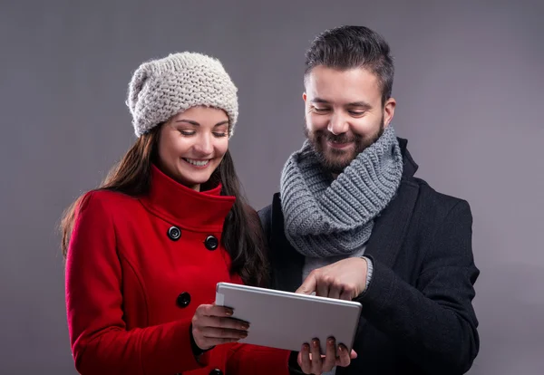 Young woman and man in winter coats with tablet — Stockfoto