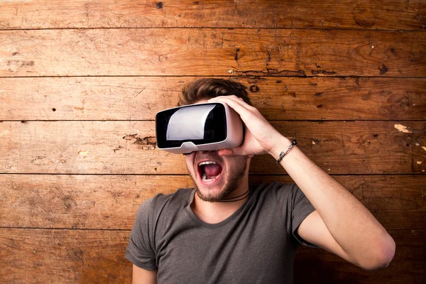Hombre con gafas de realidad virtual. Estudio plano, fondo de madera —  Fotos de Stock