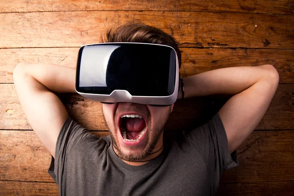 Hombre con gafas de realidad virtual. Estudio plano, fondo de madera —  Fotos de Stock