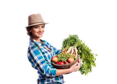 Woman, checked shirt holding basket with fruit and vegetables