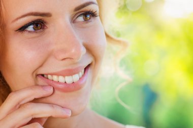 Blond woman, curly hair in green nature. Sunny summer