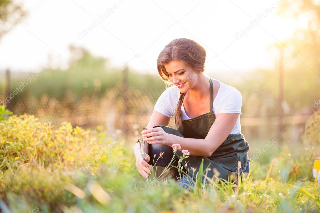 Young gardener in garden with various plants, sunny nature