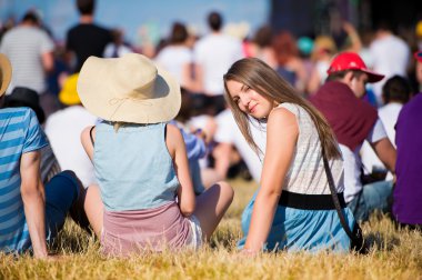Arkadaşları, gençleri, yaz festivalini, çimenlerin üzerinde oturan kız