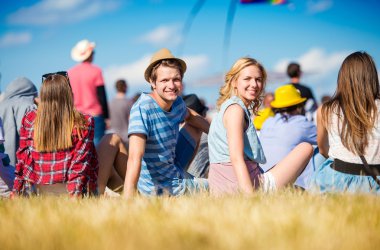 Yaz müzik festivalinde gençler, çimenlerin üzerinde oturuyor
