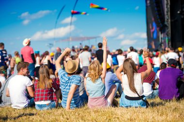 Teenagers, summer music festival, sitting in front of stage clipart