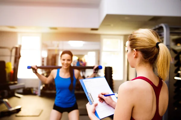 Frau trainiert im Fitnessstudio, Personal Trainer, Plan auf Klemmbrett — Stockfoto