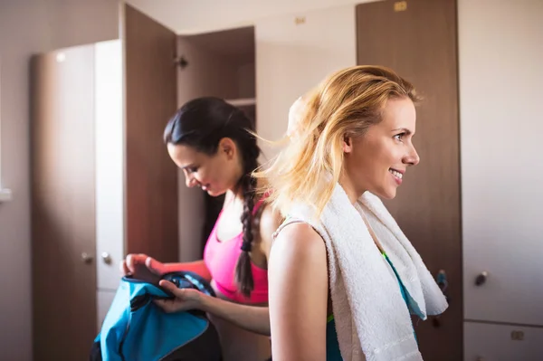 Two woman changing in locker room in gym