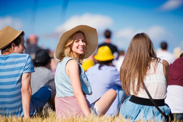 Woman with hat, teenagers, summer festival, sitting on grass — Stockfoto