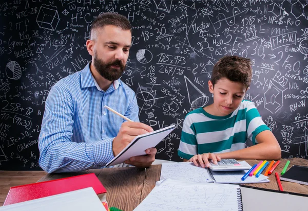 Hipster teacher with his student with calculator, big blackboard — 스톡 사진