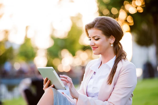 Mujer de negocios sentada en el parque trabajando en la tableta, soleado verano da —  Fotos de Stock