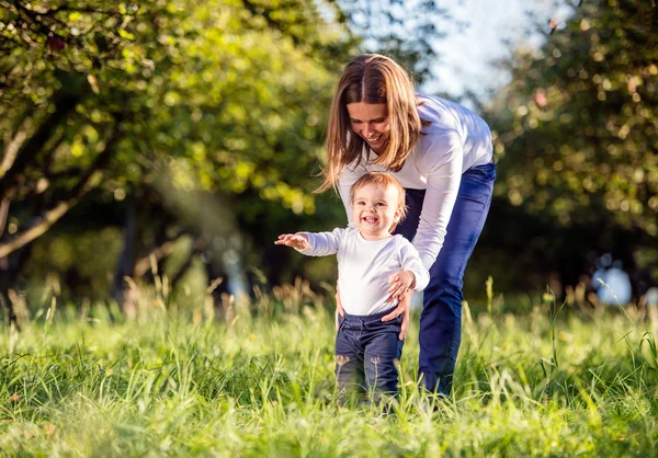 Mor som håller sin son göra första steg, grön natur — Stockfoto