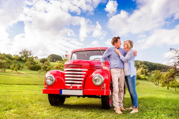 Senior couple hugging at vintage car — Stock Photo, Image