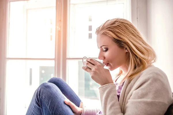 Woman on window sill drinking tea — Stock Photo, Image