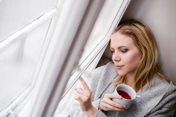 Woman on window sill with cup of tea — Stock Photo, Image