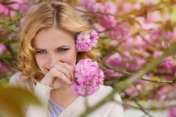 Blond kvinna mot rosa träd blossoom — Stockfoto