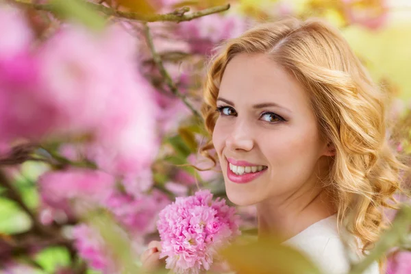 Mujer rubia contra flor de árbol rosa —  Fotos de Stock