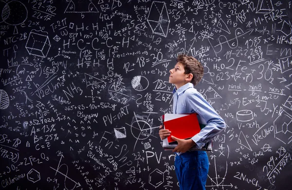 Boy with notebooks against big blackboard — Stock Photo, Image