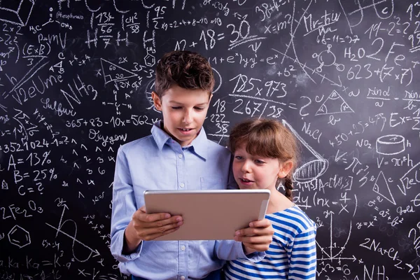 Garçon et fille avec tablette au tableau noir — Photo