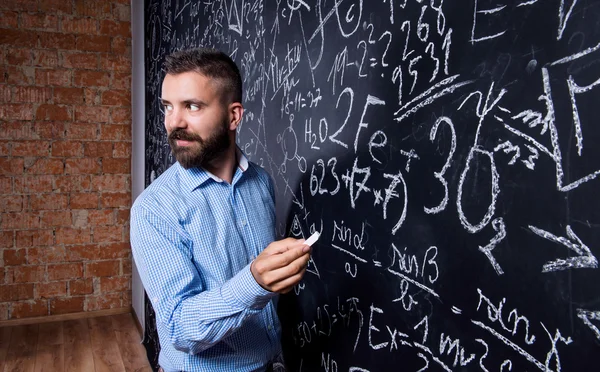 Hipster teacher writing on blackboard — Stock Photo, Image