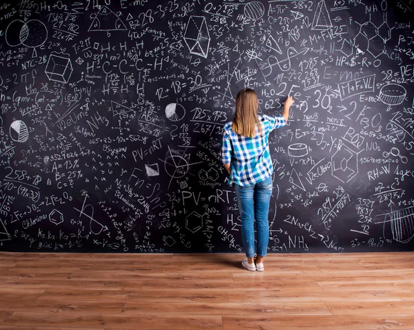 Estudante escrevendo símbolos matemáticos no quadro negro — Fotografia de Stock