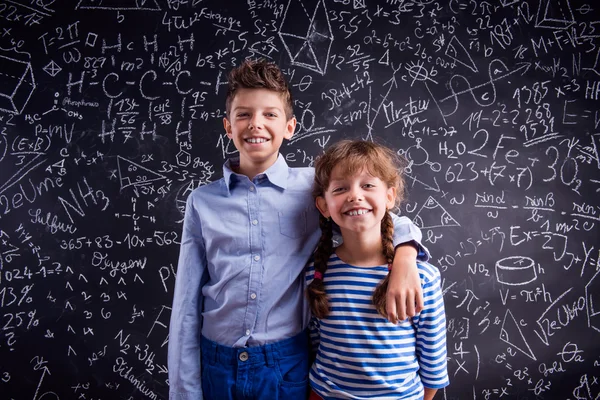 Menino e menina na escola no quadro negro . — Fotografia de Stock