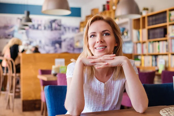 Блондинка сидит в городском кафе — стоковое фото