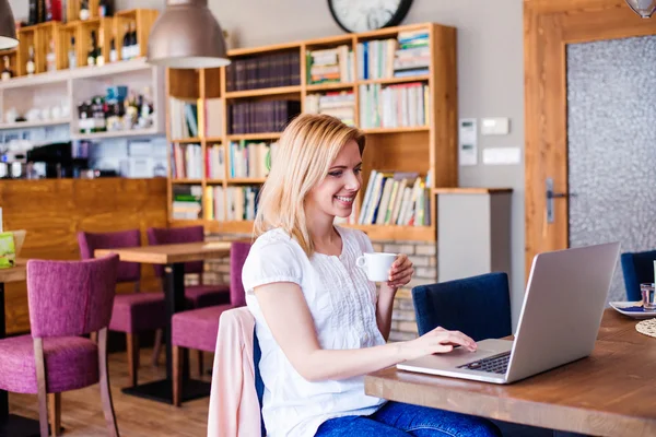 Femme blonde avec ordinateur portable dans un café — Photo