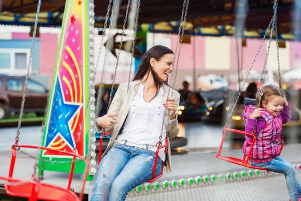 Madre e hija en la feria de la diversión, paseo en cadena swing —  Fotos de Stock