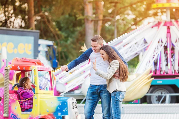 Los padres en la feria de la diversión, agitando a su hijo tomando paseo —  Fotos de Stock