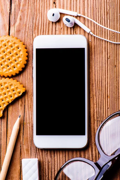 Smartphone, earphones, eyeglasses on desk — Stock Photo, Image