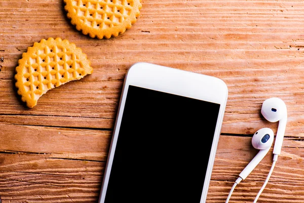 智能手机，耳机和饼干。 — 图库照片
