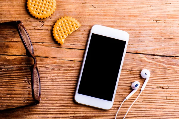 Smartphone, auriculares, anteojos en el escritorio —  Fotos de Stock