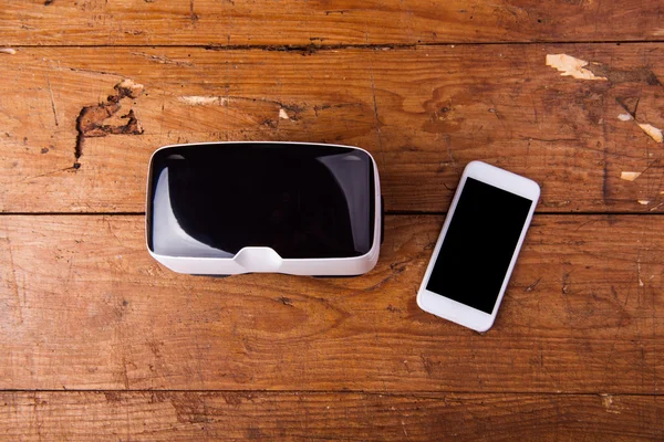 Lunettes de réalité virtuelle et téléphone intelligent sur table en bois — Photo