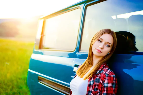 Tienermeisje glimlachend tegen groene camper buiten in de natuur — Stockfoto