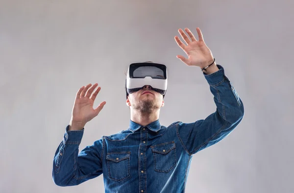 Een man met een virtual reality bril. Studio shot, grijze achtergrond — Stockfoto