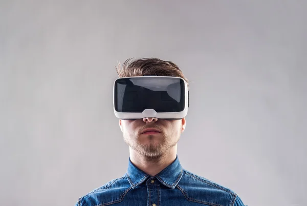 Hombre con gafas de realidad virtual. Tiro de estudio, fondo gris — Foto de Stock