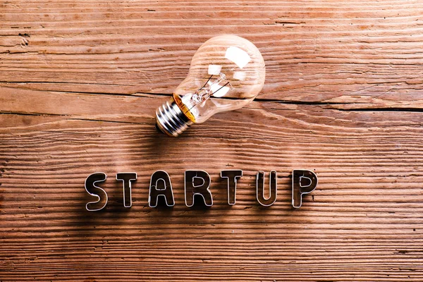 Office desk with start up sign and light bulb. — Stock Photo, Image