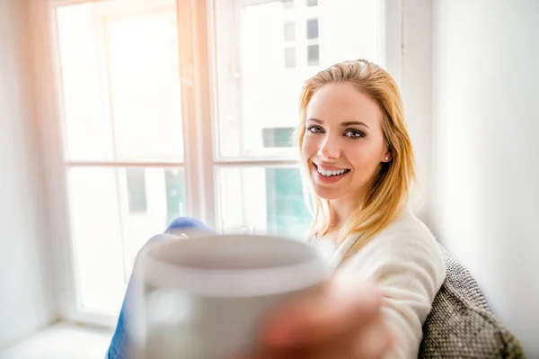 Mujer en alféizar de la ventana sosteniendo una taza de café —  Fotos de Stock