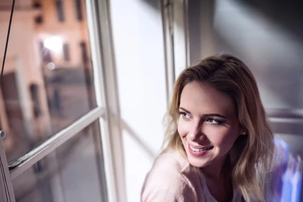 Woman smiling sitting on windowsill — Stock Photo, Image